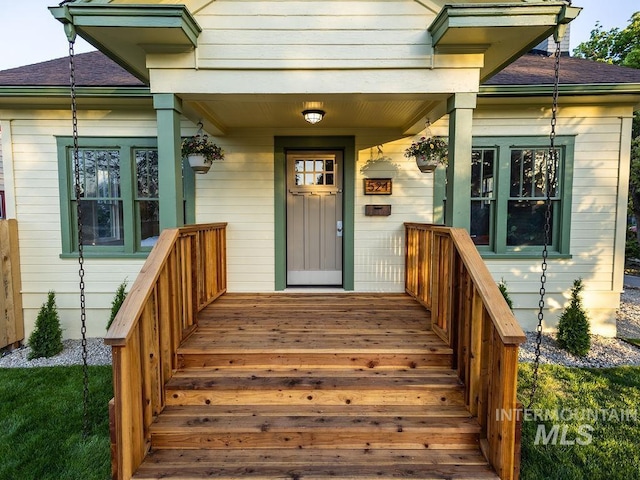 view of exterior entry featuring a porch and a shingled roof
