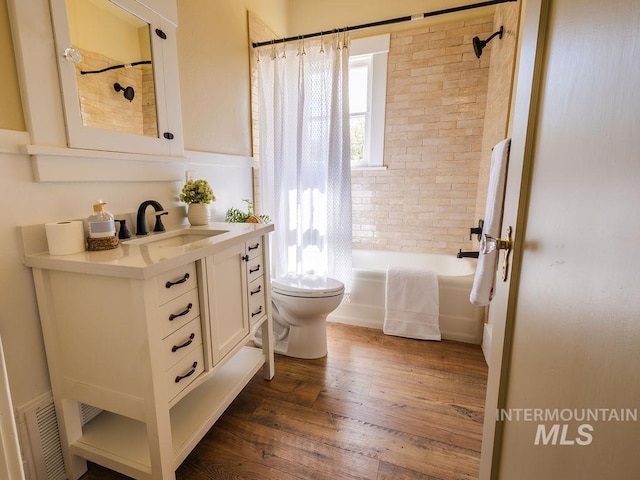 bathroom featuring visible vents, wood finished floors, shower / tub combo, vanity, and toilet