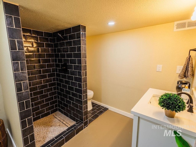 bathroom with toilet, a textured ceiling, recessed lighting, visible vents, and tiled shower