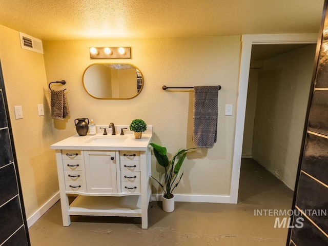 bathroom featuring vanity, baseboards, concrete flooring, and visible vents