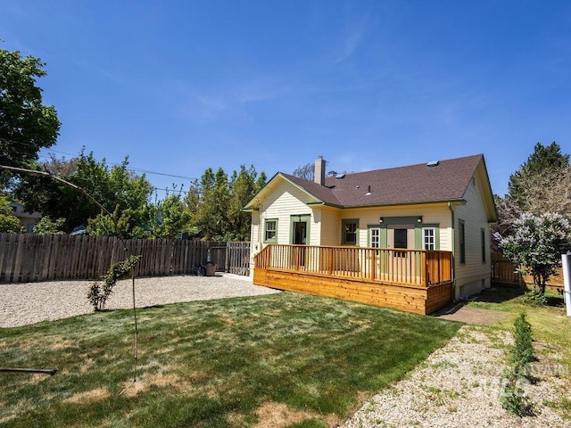 back of property featuring a chimney, a lawn, a deck, a fenced backyard, and a patio