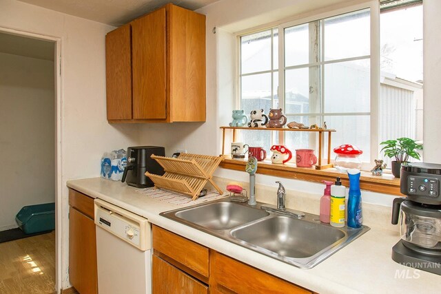 134 Maple Ave, Hansen, ID 83334 - kitchen featuring white dishwasher, a sink, light countertops, wood finished floors, and brown cabinetry