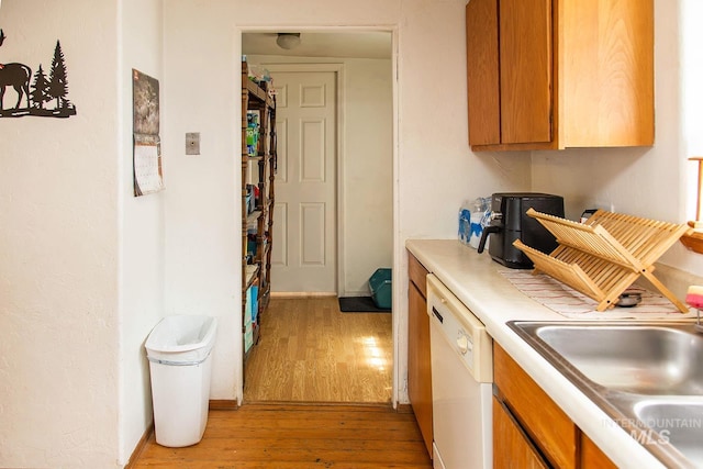 134 Maple Ave, Hansen, ID 83334 - kitchen featuring white dishwasher, light wood-type flooring, a sink, and brown cabinetry