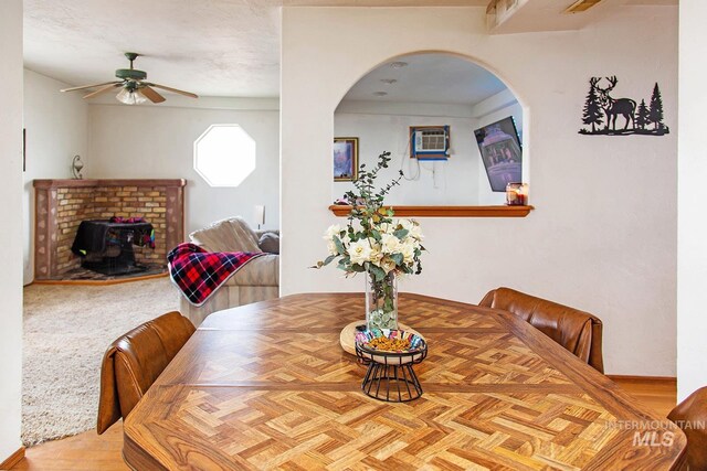 134 Maple Ave, Hansen, ID 83334 - dining space featuring ceiling fan, a wood stove, arched walkways, and a wall mounted air conditioner