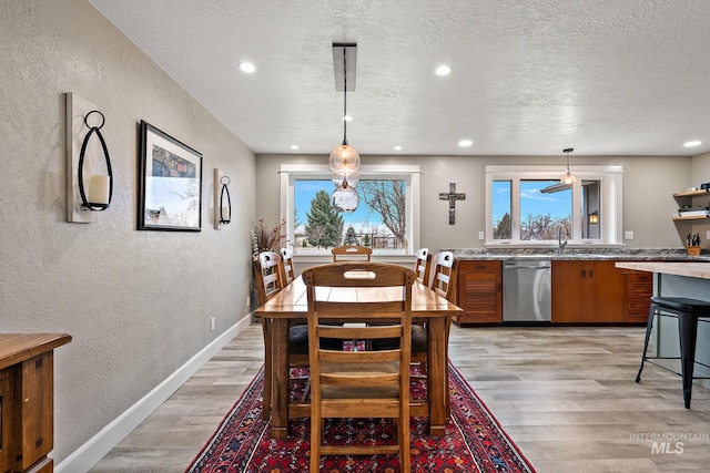 dining space featuring a textured ceiling, recessed lighting, light wood finished floors, baseboards, and a textured wall