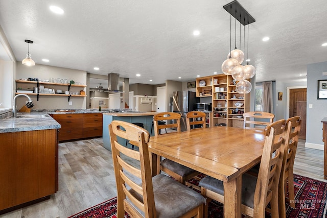 dining area with light wood finished floors, recessed lighting, a textured ceiling, and baseboards