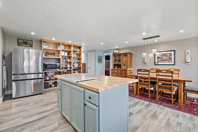 kitchen with light wood finished floors, a kitchen island, open shelves, stainless steel appliances, and wood counters