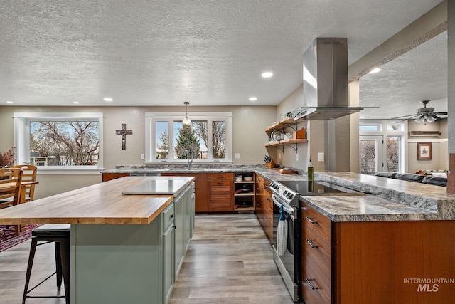 kitchen featuring butcher block countertops, light wood-style flooring, electric stove, island range hood, and open shelves