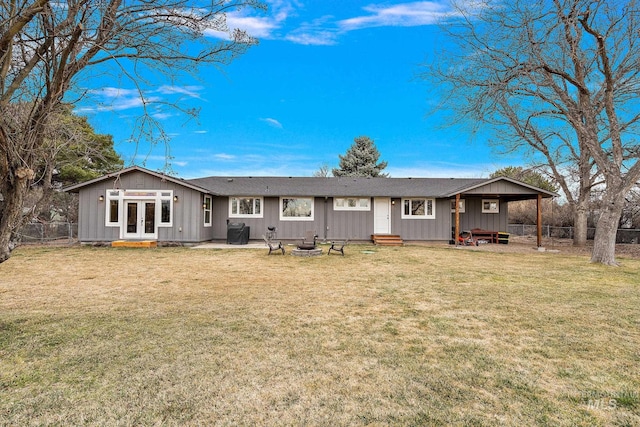 back of property featuring fence, an outdoor fire pit, entry steps, french doors, and a lawn