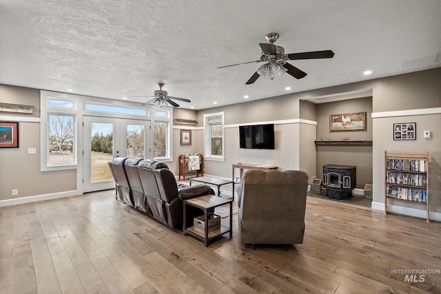 living room featuring hardwood / wood-style floors, a wood stove, recessed lighting, french doors, and a textured ceiling