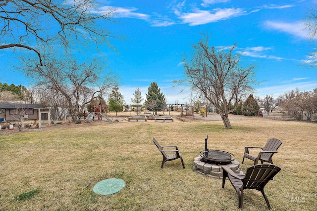 view of yard featuring a fire pit, a playground, and a vegetable garden