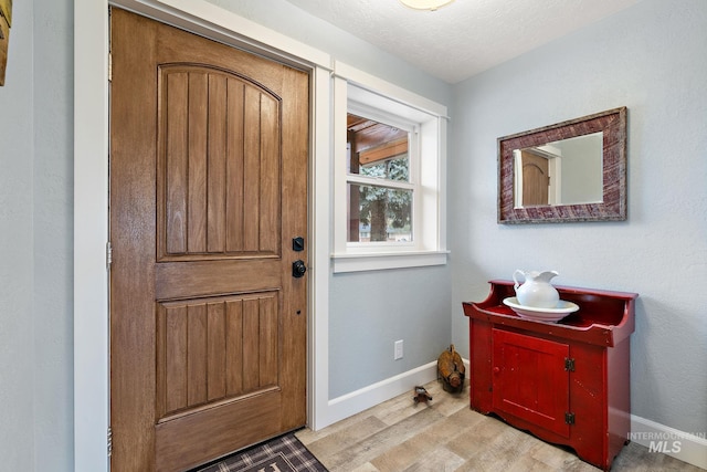 foyer with a textured ceiling, baseboards, and wood finished floors