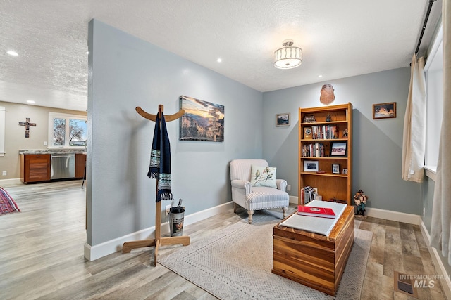 living area featuring recessed lighting, light wood-style flooring, a textured ceiling, and baseboards