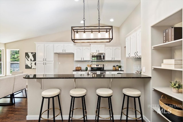 6472 S Liveoak Pl, Boise, ID 83716 - kitchen with stainless steel appliances, vaulted ceiling, white cabinets, backsplash, and a peninsula