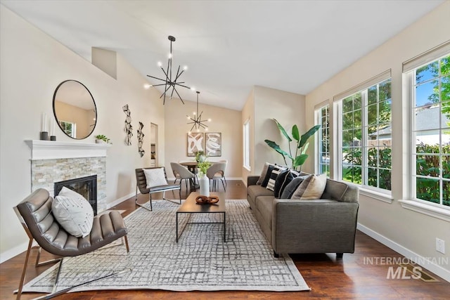 6472 S Liveoak Pl, Boise, ID 83716 - living room with a chandelier, a stone fireplace, vaulted ceiling, wood finished floors, and baseboards