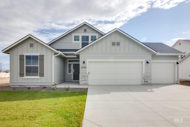 view of front of property with a garage, a front lawn, board and batten siding, and roof with shingles