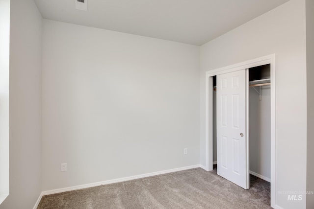 unfurnished bedroom with a closet, carpet flooring, and baseboards