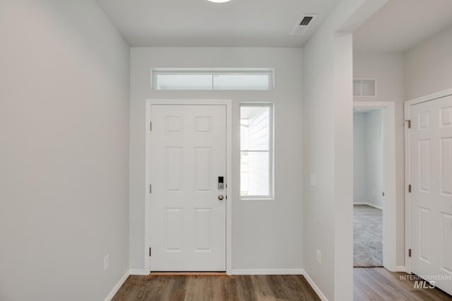 foyer featuring visible vents, baseboards, and wood finished floors