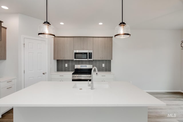 kitchen featuring stainless steel appliances, light wood finished floors, backsplash, and light countertops