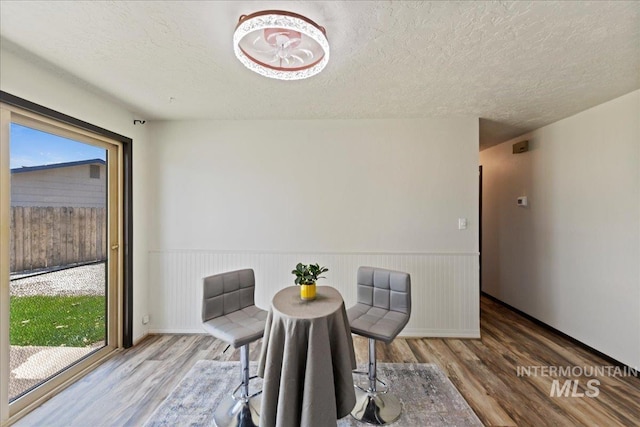 406 N Pine St, Emmett, ID 83617 - dining space with wood finished floors, a textured ceiling, and wainscoting
