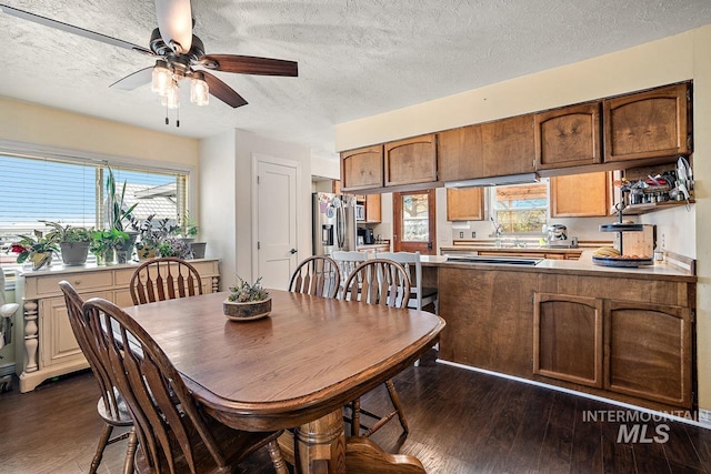 dining room with a textured ceiling, ceiling fan, and dark wood-type flooring