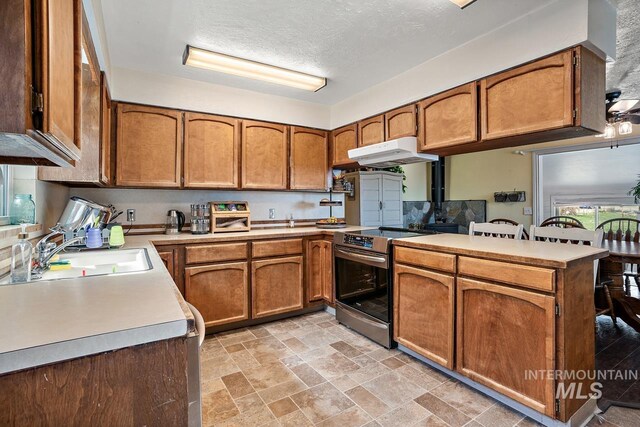 kitchen featuring sink, kitchen peninsula, extractor fan, a textured ceiling, and stainless steel electric stove