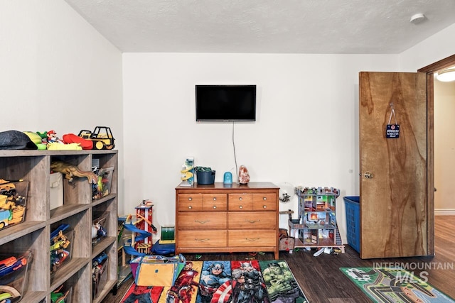 playroom with dark wood-type flooring and a textured ceiling