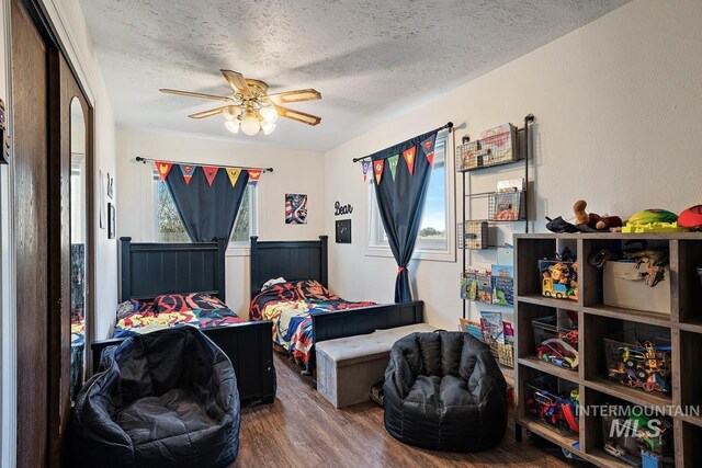 bedroom with multiple windows, ceiling fan, hardwood / wood-style floors, and a textured ceiling