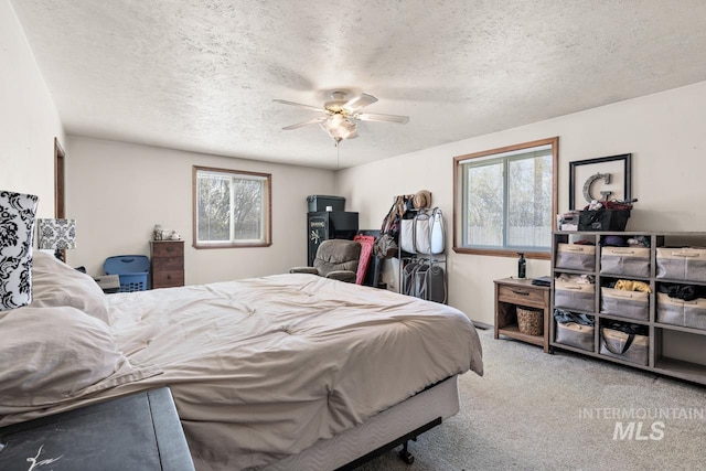 carpeted bedroom featuring a textured ceiling, multiple windows, and ceiling fan