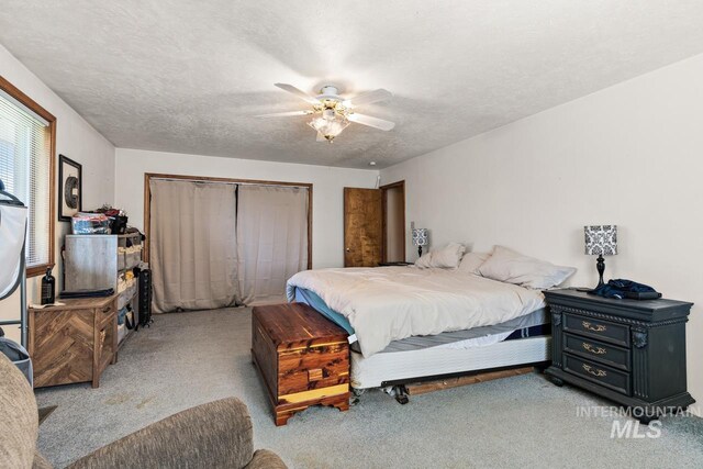 bedroom with ceiling fan, a closet, light carpet, and a textured ceiling