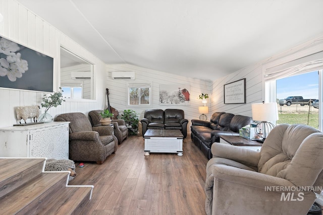 living room featuring wooden walls, dark hardwood / wood-style flooring, a wall unit AC, and vaulted ceiling