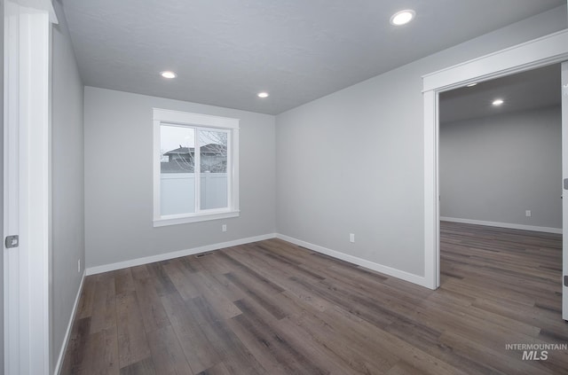 spare room with dark wood-type flooring, recessed lighting, visible vents, and baseboards