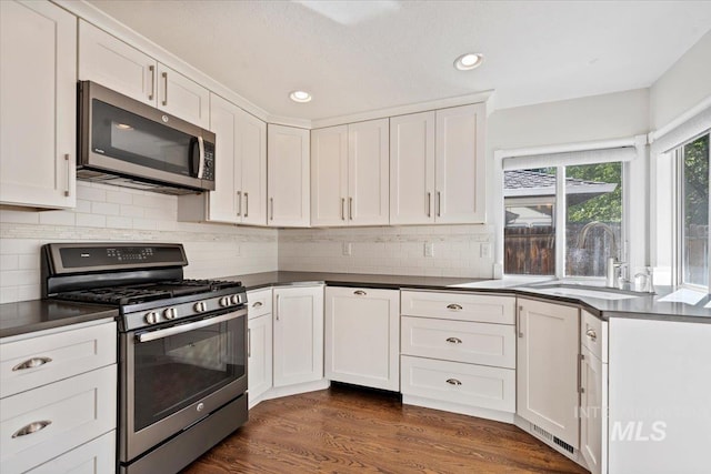 1825 E Seaside Ct, Boise, ID 83706 - kitchen featuring appliances with stainless steel finishes, a sink, dark countertops, white cabinets, and recessed lighting