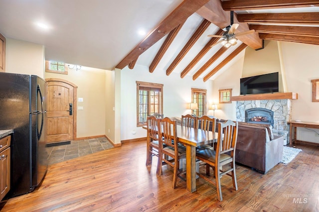 dining space featuring beam ceiling, a fireplace, ceiling fan, high vaulted ceiling, and dark wood-type flooring