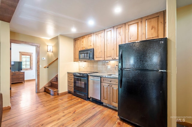 kitchen featuring tasteful backsplash, light hardwood / wood-style floors, stone countertops, sink, and black appliances