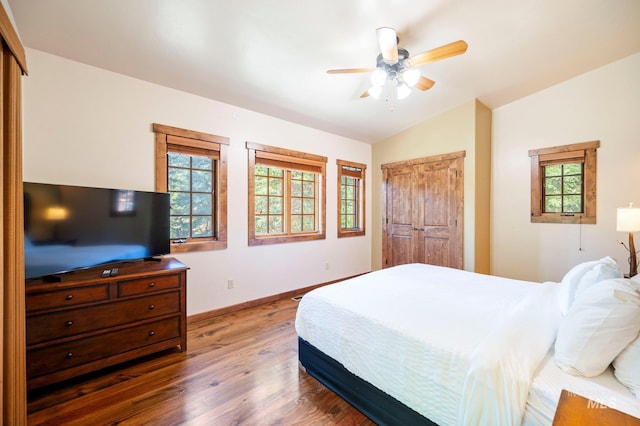 bedroom featuring ceiling fan, dark wood-type flooring, multiple windows, and lofted ceiling