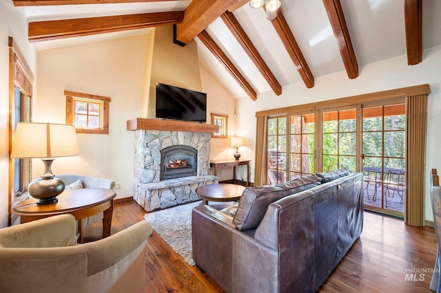 living room featuring beam ceiling, a stone fireplace, and wood-type flooring