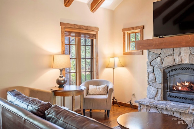 living room featuring a fireplace, light wood-type flooring, a healthy amount of sunlight, and beam ceiling