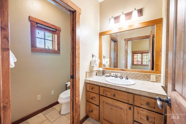 bathroom with a wealth of natural light, tile patterned floors, toilet, and vanity