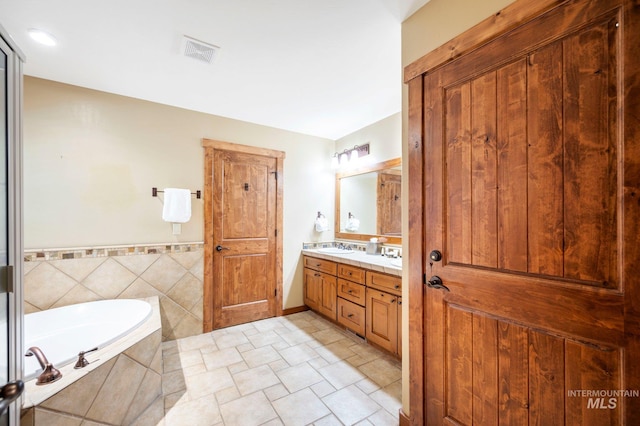 bathroom featuring tile patterned floors, tiled tub, and vanity