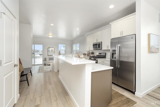 kitchen with stainless steel appliances, plenty of natural light, a kitchen island with sink, and white cabinets