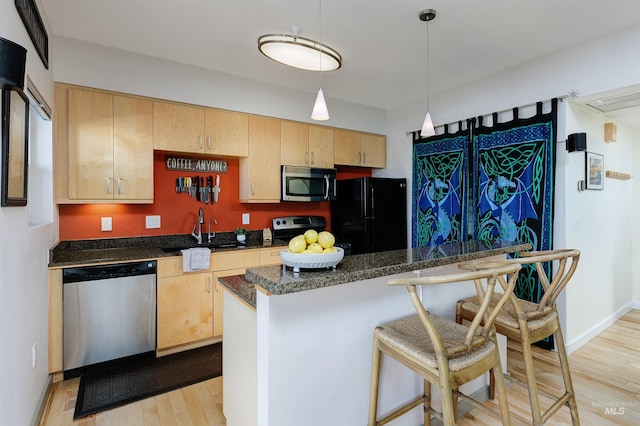 502 S 15th St # 104, Boise, ID 83702 - kitchen with a kitchen breakfast bar, stainless steel appliances, a sink, a kitchen island, and light wood-style flooring