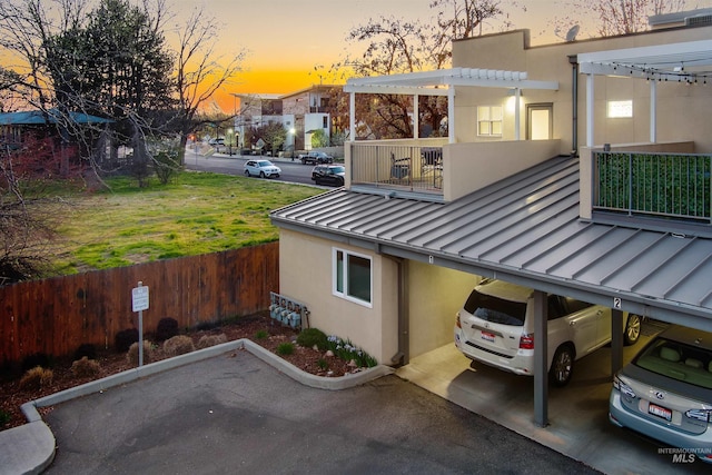 502 S 15th St # 104, Boise, ID 83702 - property exterior at dusk with fence, a balcony, stucco siding, a standing seam roof, and metal roof