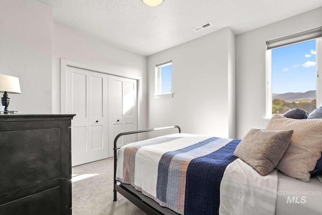 bedroom featuring a closet, visible vents, carpet floors, and a textured ceiling