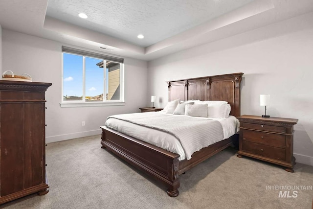 bedroom with baseboards, recessed lighting, a textured ceiling, a raised ceiling, and light colored carpet