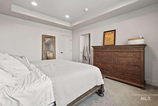 bedroom featuring recessed lighting, visible vents, a raised ceiling, and light carpet