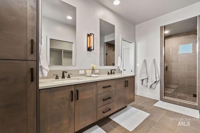 bathroom featuring a shower stall, double vanity, tile patterned floors, and a sink