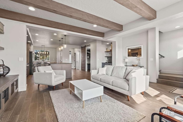 living room with beam ceiling, recessed lighting, stairs, dark wood-type flooring, and a barn door