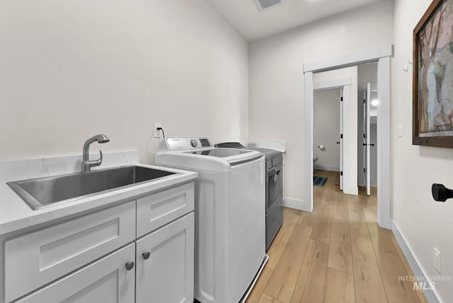 44 Shoemaker Dr, Horseshoe Bend, ID 83629 - washroom with cabinet space, washing machine and clothes dryer, light wood-style flooring, and baseboards