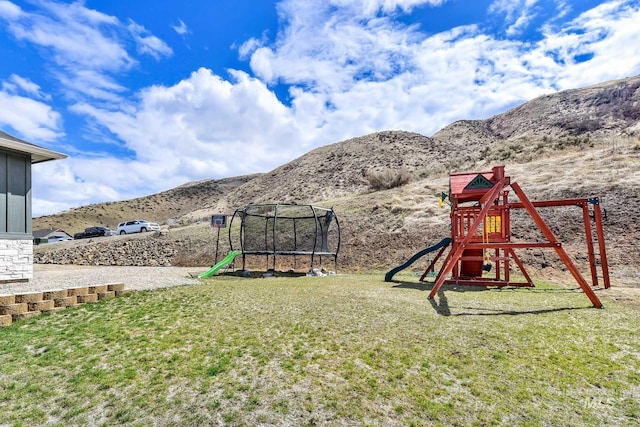 44 Shoemaker Dr, Horseshoe Bend, ID 83629 - view of grassy yard with a trampoline, a playground, and a mountain view